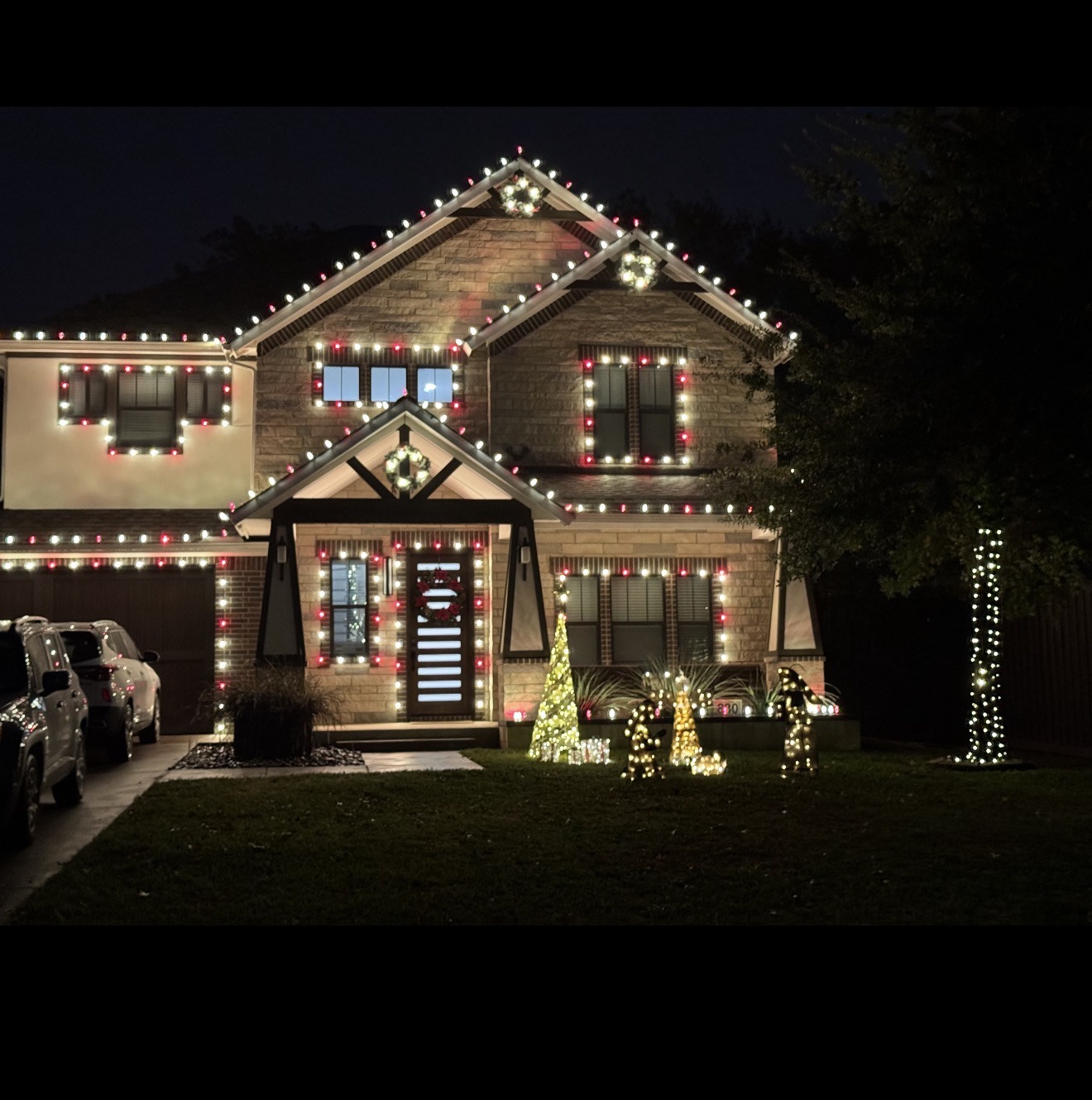 Red and white Christmas light installation on a two-story home